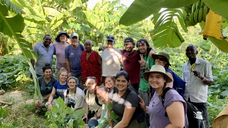 A group of U N E students and guides pose in a jungle in Kenya